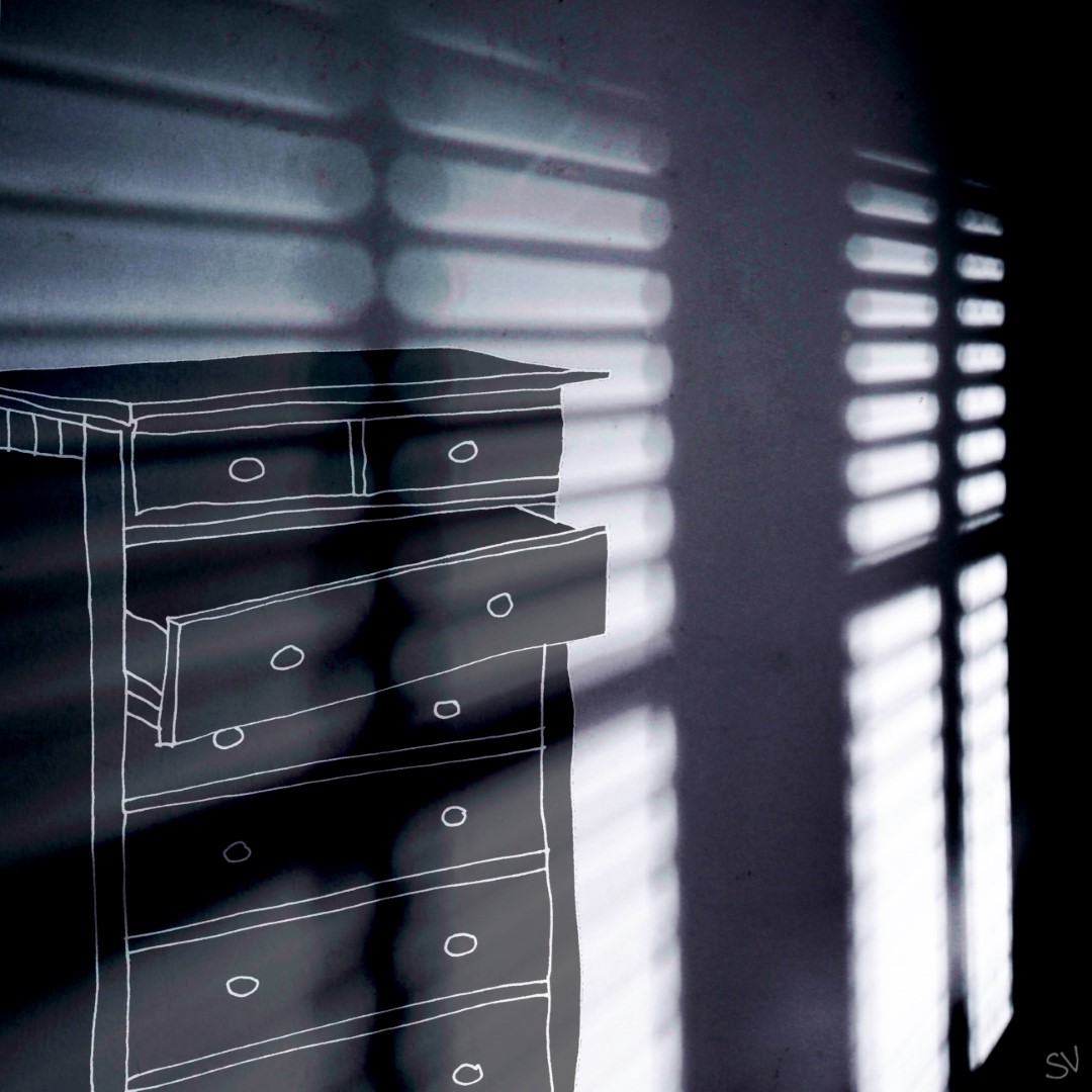 Une commode dont le deuxième tiroir est ouvert, dans une chambre uniquement éclairée par une lumière bleutée entrant par les lamelles des stores.